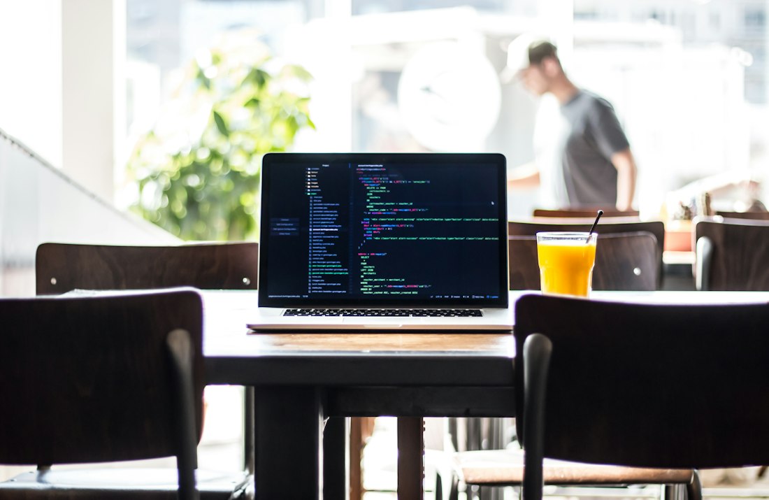 A laptop on a wooden table in a sunny café